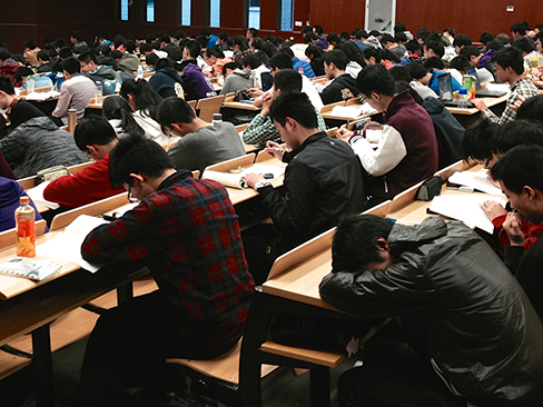 Muchos estudiantes que estudian en una gran sala de conferencias