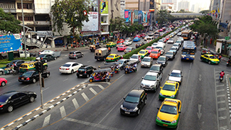 Esta es una imagen de una calle de la ciudad con una señal de tráfico. El cuadro tiene carriles de tránsito muy transitados en ambas direcciones.