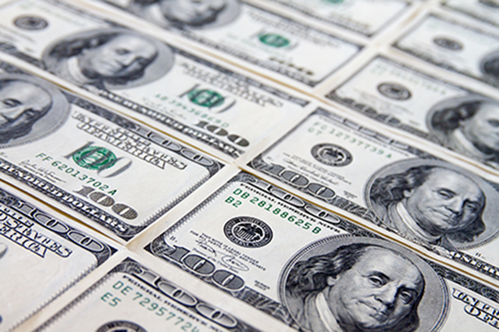 Une photographie montre une surface plane recouverte de billets de 100$.