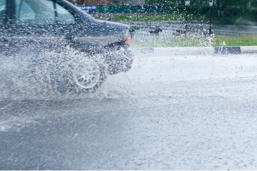 A car splashing through a puddle of rain water.