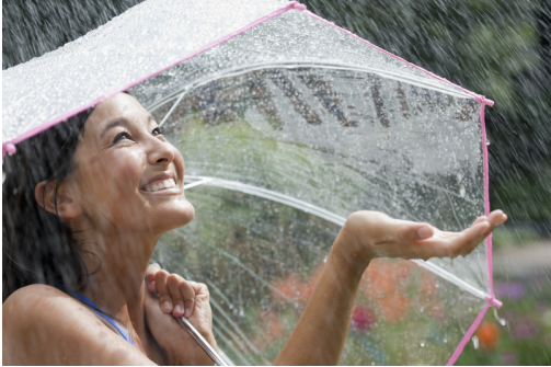 A woman standing in the rain under an umbrella.