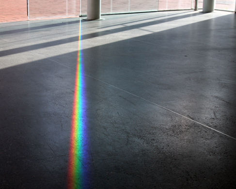 Una foto de un rayo de luz de color arcoíris que se extiende por el suelo.