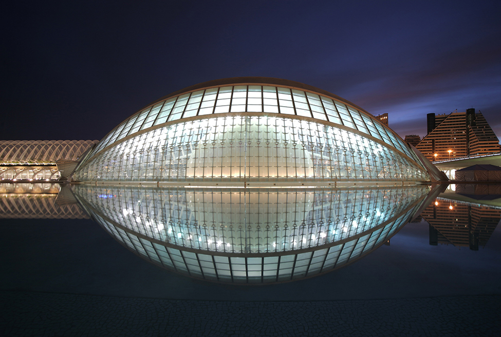 Una foto de una cúpula ovoide de vidrio reflejándose en el agua para hacer algo así como una forma de fútbol.